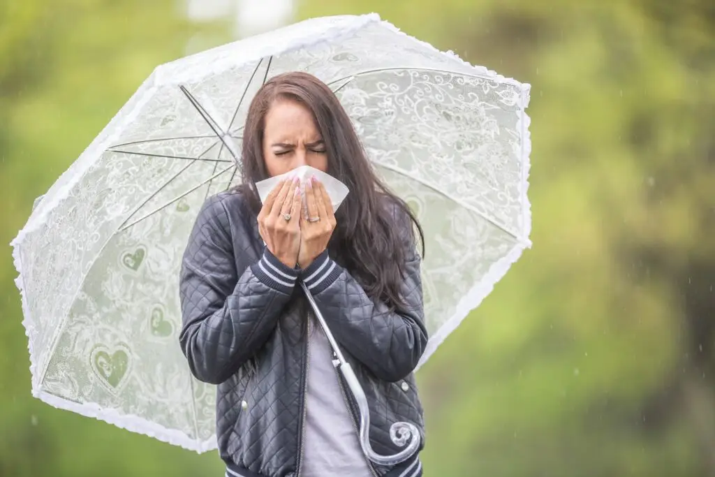 gambar seorang perempuan bersin saat musim hujan. Tips jaga daya tahan tubuh di musim penghujan